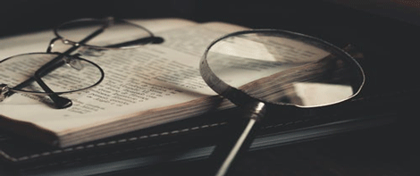 Eyeglasses and magnifying glass on top of open book