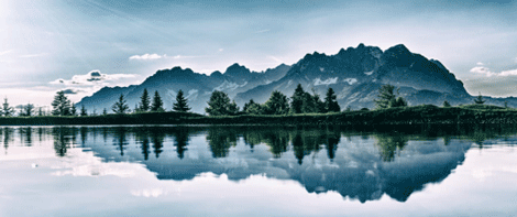 Mountain and pine trees reflected in lake